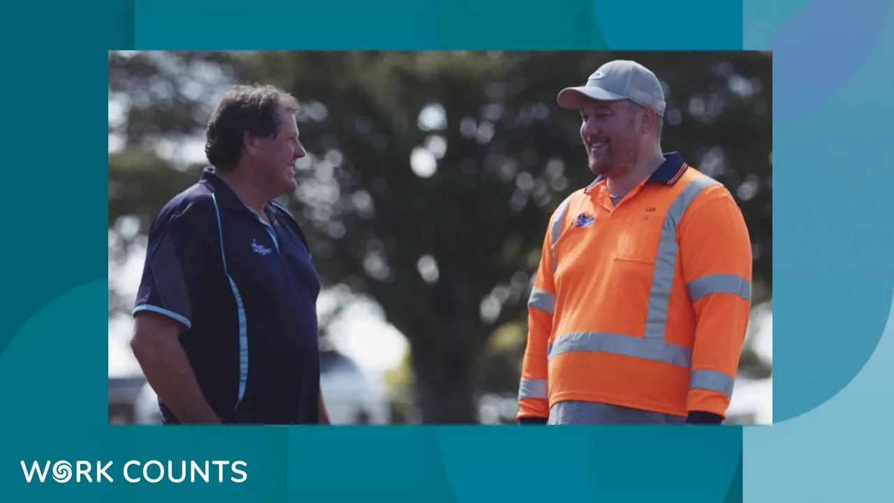 Two men talking together outdoors. One is wearing high vis safety clothing